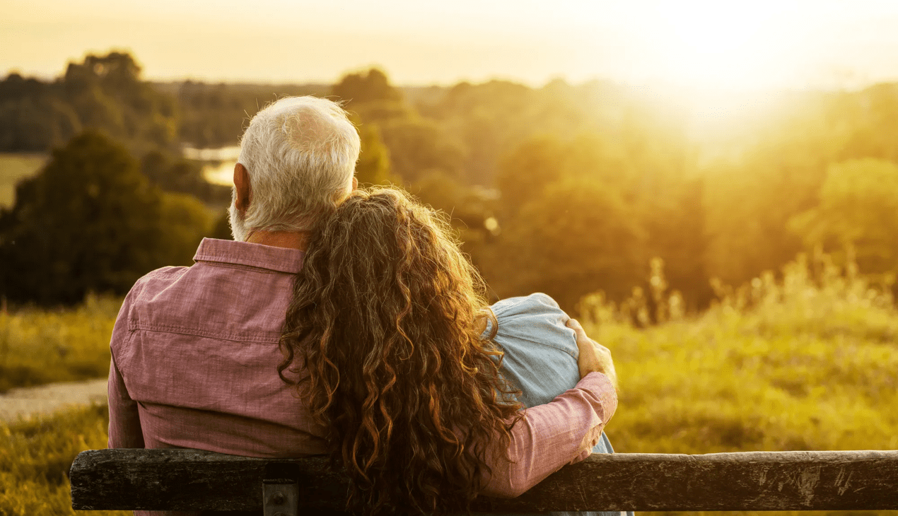 couple sitting on bench with sunset in background